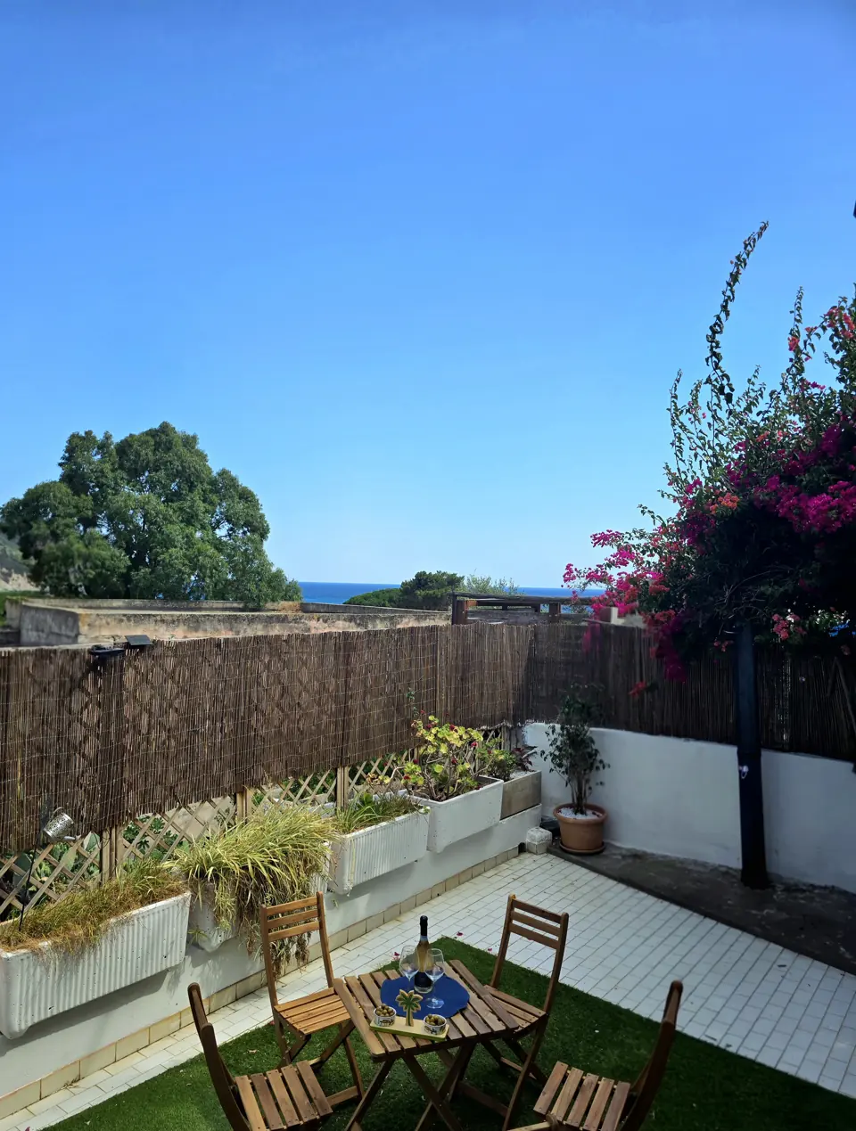 Il giardino-terrazza con il tavolo, la bouganville e uno scorcio di mare