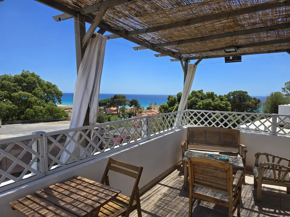 La terrazza sotto il pergolato, con il mare tra i pini